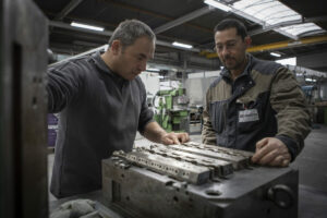 deux opérateurs qui sont entrain de regarder une press, ils sont dans un atelier